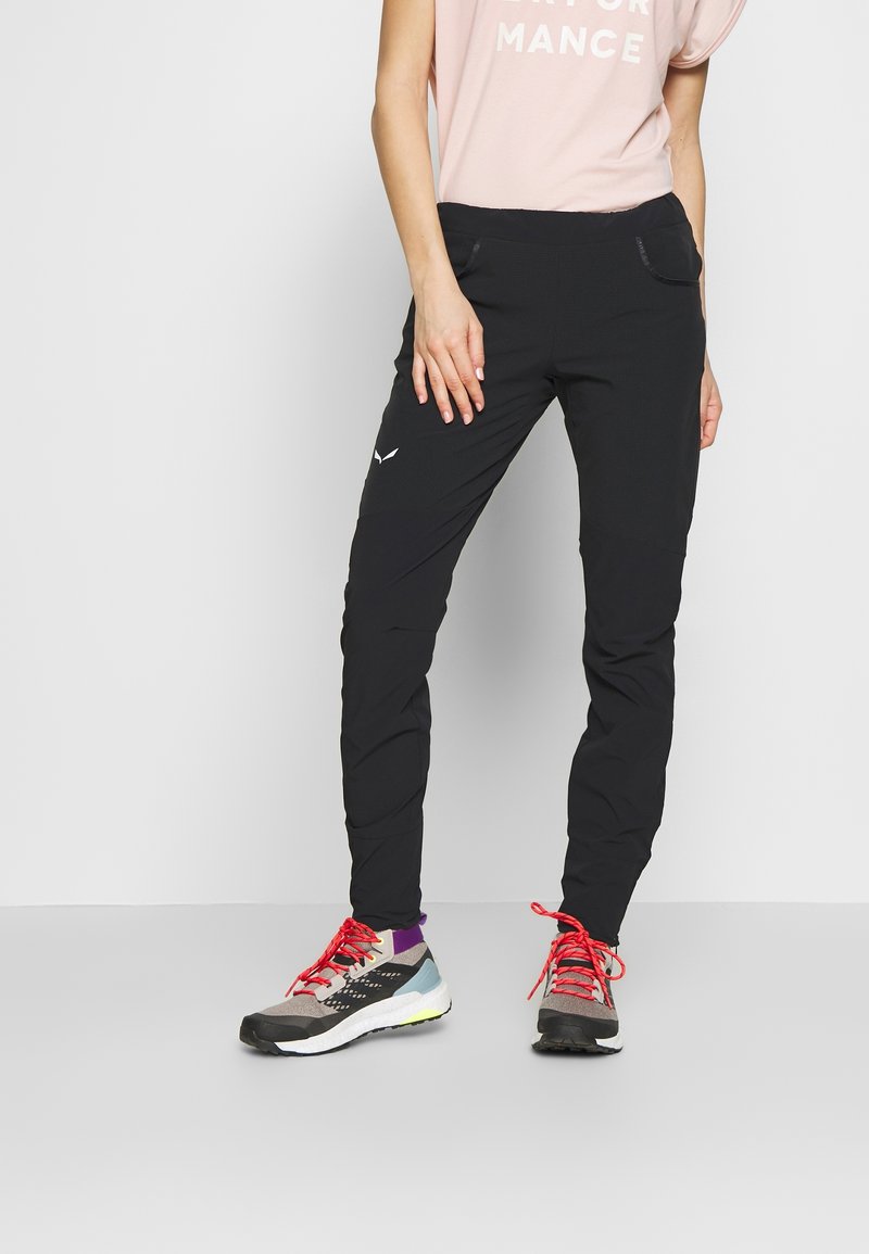 Svarta träningsbyxor med slim fit, som har sidofickor, texturerat tyg och diskret branding. Bärs tillsammans med flerfärgade terränglöparskor.