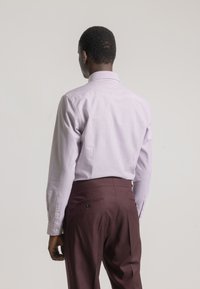 Camisa de manga larga a rayas en púrpura pálido y blanco, combinada con pantalones burdeos oscuros. Presenta un cuello clásico y puños abotonados.