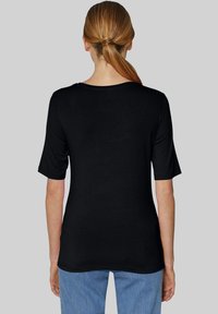 Schwarzes kurzärmeliges T-Shirt mit rundem Halsausschnitt, glatter Textur und einem einfachen, klassischen Design, kombiniert mit hellblauen Jeans.