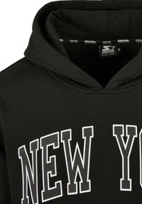 Černá mikina s velkým bílým nápisem "NEW YORK". Vyrobena z hladké tkaniny, s klasickým střihem na přetahování a prostornou kapucí.