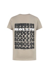 Beige katoenen t-shirt met korte mouwen en een grafisch ontwerp met donkere tekst op de achterkant. Het ontwerp bevat patronen en een logo.
