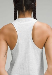 Light gray sleeveless tank top with a racerback design, featuring a soft texture and minimal branding near the neckline, showing bare shoulders.