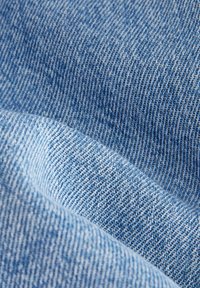 Gros plan sur un tissu denim bleu clair et bleu foncé montrant une texture tissée et un motif diagonal sergé.