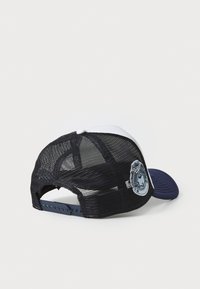 Lastbilcap med en solid marineblå skygge, hvid frontpanel og sort mesh bag, med en rund patchdetalje på venstre side.