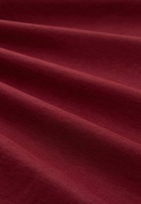 Zacht kastanjebruin stof met subtiele diagonale kreukels, die de textuur en kleurdiepte benadrukken.