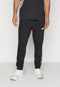 Pantaloni de trening negri din bumbac, cu un logo turquoise și dungi de accent pe laterale, cu manșete ribbate și o croială lejeră.