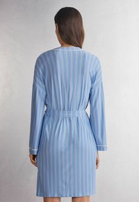Blauwe en witte gestreepte kamerjas met lange mouwen, een riem op de taille en een gladde stof. Heeft verticale strepen en een klassieke kraag.