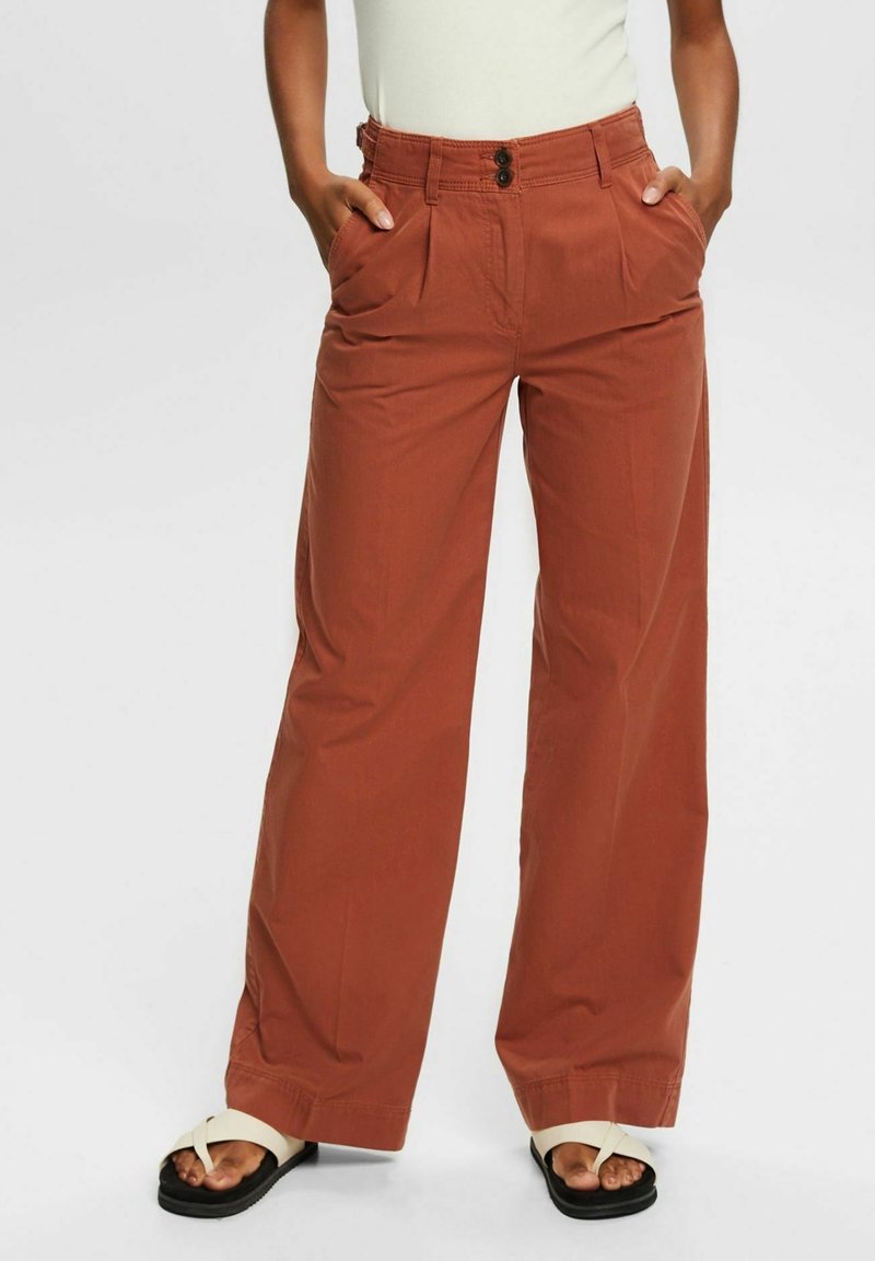 Pantalon large couleur rouille en tissu léger, avec plis sur le devant, deux poches latérales et une fermeture à bouton à la taille.