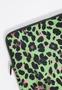 Borsetta in neoprene con sfondo verde, caratterizzata da macchie di leopardo nere e sottili accenti rosa. Chiusura con zip nera.