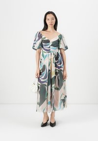 Blumenmuster Midi-Kleid aus durchscheinendem Stoff mit Puffärmeln, V-Ausschnitt und Empire-Taille. Kombiniert mit einer weißen Tasche.