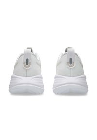 Chaussures de sport blanches avec un talon texturé, un col rembourré et une languette. Elles présentent une épaisse semelle blanche avec un design ondulé et des accents minimalistes.
