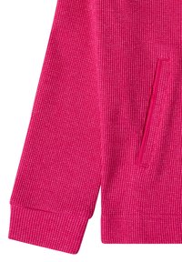 Zbliżenie jasnoróżowego rękawa o strukturze dzianiny waflowej oraz bocznej kieszeni długiego rękawa z detalami ściągacza na mankiecie.