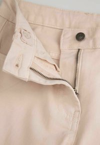 Jasno beżowe spodnie khaki z zamek błyskawicznym z przodu, metalowym zapięciem na guzik oraz subtelną teksturowaną tkaniną. Posiadają przeszycia oraz wygodny pas.