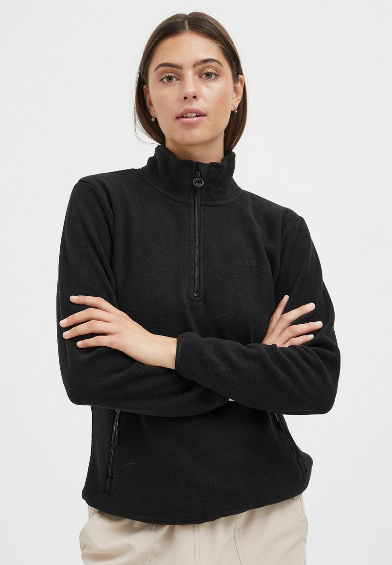 Pullover en polaire noir avec un col haut, zip quart et poches latérales. Texture douce avec un design simple et sans logos visibles.