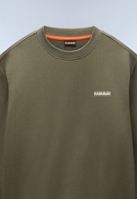Olijfgroene sweatshirt met ronde hals, voorzien van een klein wit logo op de borst en een oranje accent binnen de halslijn. Glad textuur.