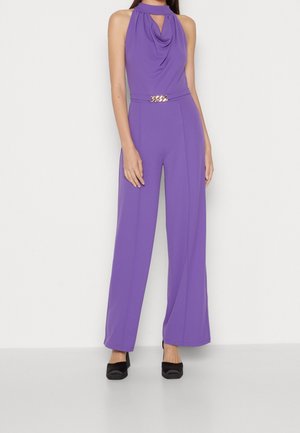 Paarse mouwloze jumpsuit met gedrapeerde halslijn, keyhole-uitgesneden, taille met riem en gouden beslag, en broek met wijd uitlopende pijpen.