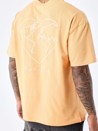 Katoenen T-shirt in lichtoranje, met een witte hartvormige graphic van de wereld en de tekst "Project x Paris" op de achterkant.