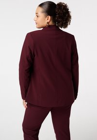 Bordeaux gepersonaliseerde blazer met een notch lapel, gestructureerde schouders en decoratieve knopen op de mouwen. Gladde stof met een getailleerd silhouet.