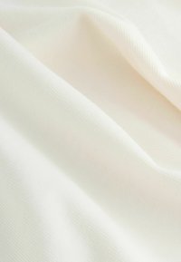 Lagani, teksturirani kremasti materijal s suptilnim uzorkom tkanja, prikazuje meko padanje i blage nabore. Idealan za odjeću ili tapeciranje.