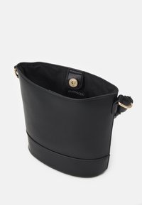 Czarna skórzana torba listonoszka z zapięciem na złoty magnetyczny zatrzask i regulowanym paskiem na jednolitym białym tle.