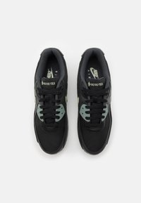 Scarpe Nike Air nere con tomaia in Gore-Tex, superficie texturizzata, pannelli in rete, dettagli verdi sui lati e lacci neri.