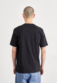 Černé bavlněné tričko s krátkým rukávem, kulatým výstřihem a hladkým povrchem. Zadní strana má jednoduchý design bez ozdob.