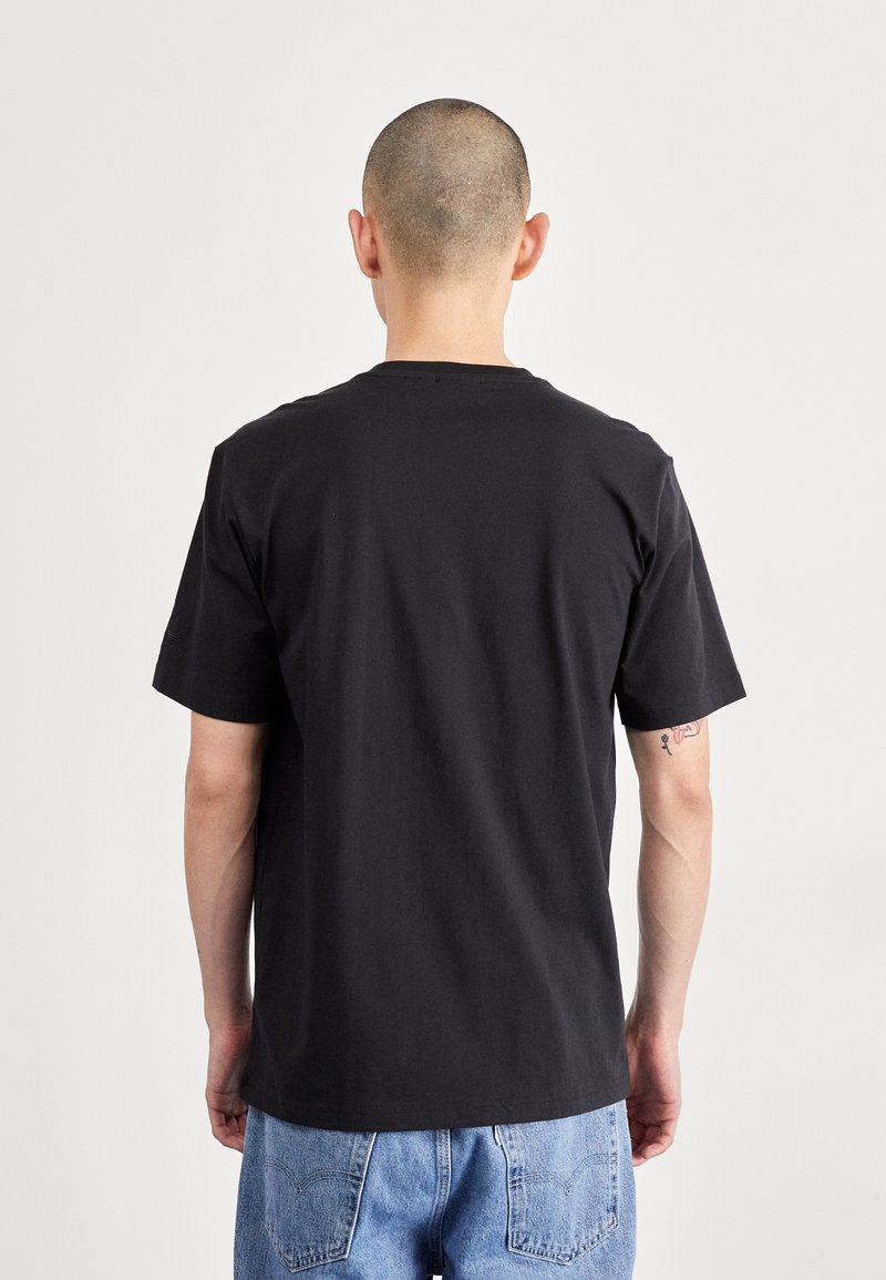 Černé bavlněné tričko s krátkým rukávem, kulatým výstřihem a hladkým povrchem. Zadní strana má jednoduchý design bez ozdob.