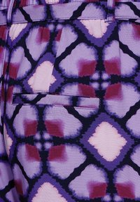 Un tessuto multicolore presenta un motivo geometrico nelle tonalità di viola, rosa e borgogna; include una tasca laterale con un lembo cucito.