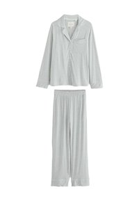 Grå pyjamasset som består av en långärmad knäpptröja med bröstficka och matchande byxor med elastisk midja, båda tillverkade av mjukt tyg.