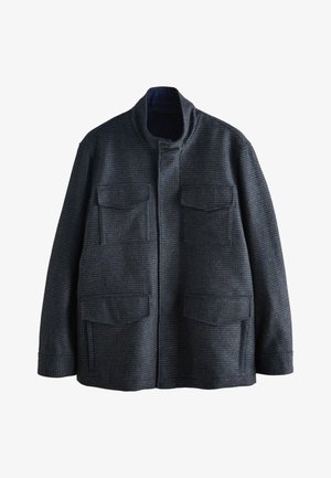 Veste en laine gris foncé avec col montant, quatre poches avant à rabats et fermeture avant par boutons, motif à carreaux texturé.