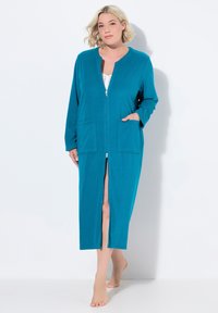 Accappatoio lungo teal con zip, maniche lunghe, due tasche frontali e una spacco davanti. Realizzato in tessuto morbido, presenta un design semplice senza motivi.