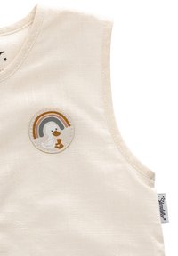 Cremefarbene ärmellose Bluse aus strukturiertem Stoff, mit einem runden Aufnäher, der eine Ente und einen Regenbogen in sanften Farben darstellt.