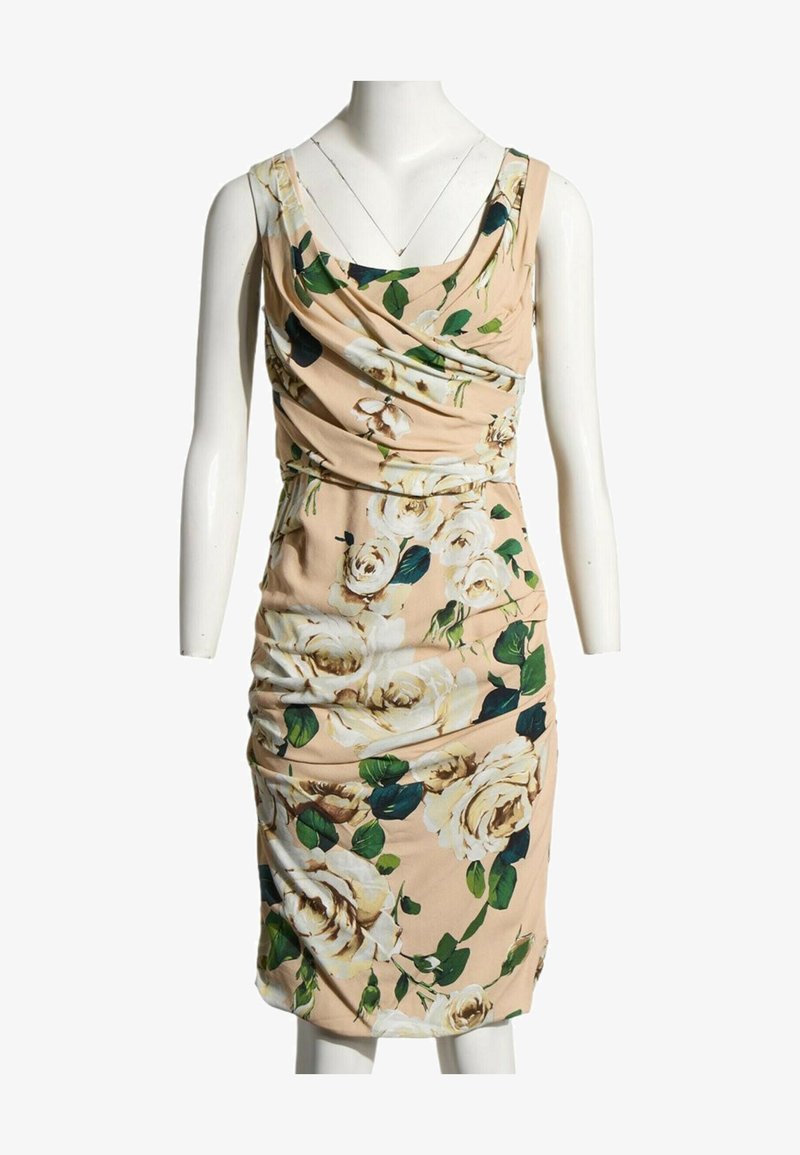 Robe beige sans manches avec imprimé de roses blanches et feuilles vertes, avec un décolleté drapé et une taille froncée, présentée sur un mannequin blanc.