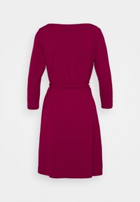 Robe longue à manches longues, longueur jusqu'aux genoux, de couleur magenta foncé, avec une ceinture ajustée à la taille, vue de dos sur fond blanc.