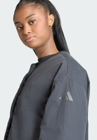 Čierna bomber bunda s textúrovaným povrchom, s predným zapínaním, rebrovaným golierom a detailom loga na rukáve.