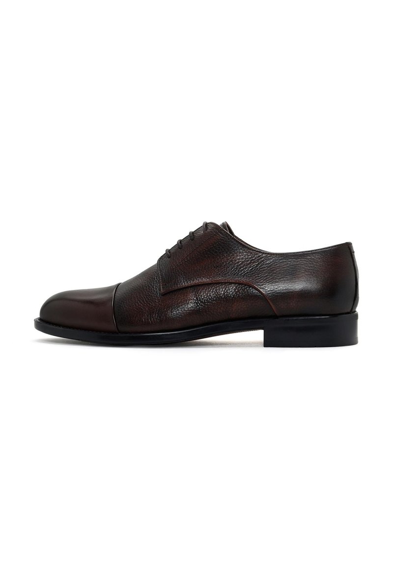 Zapato de vestir de cuero marrón con una puntera lisa, cuerpo texturizado y cuatro ojales. Presenta una suela baja de goma negra. Diseño clásico.