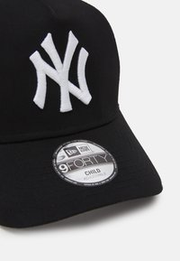 Black adjustable cap featuring white embroidered "NY" logo. Includes a circular tag reading "New Era 9FORTY Child Adjustable."