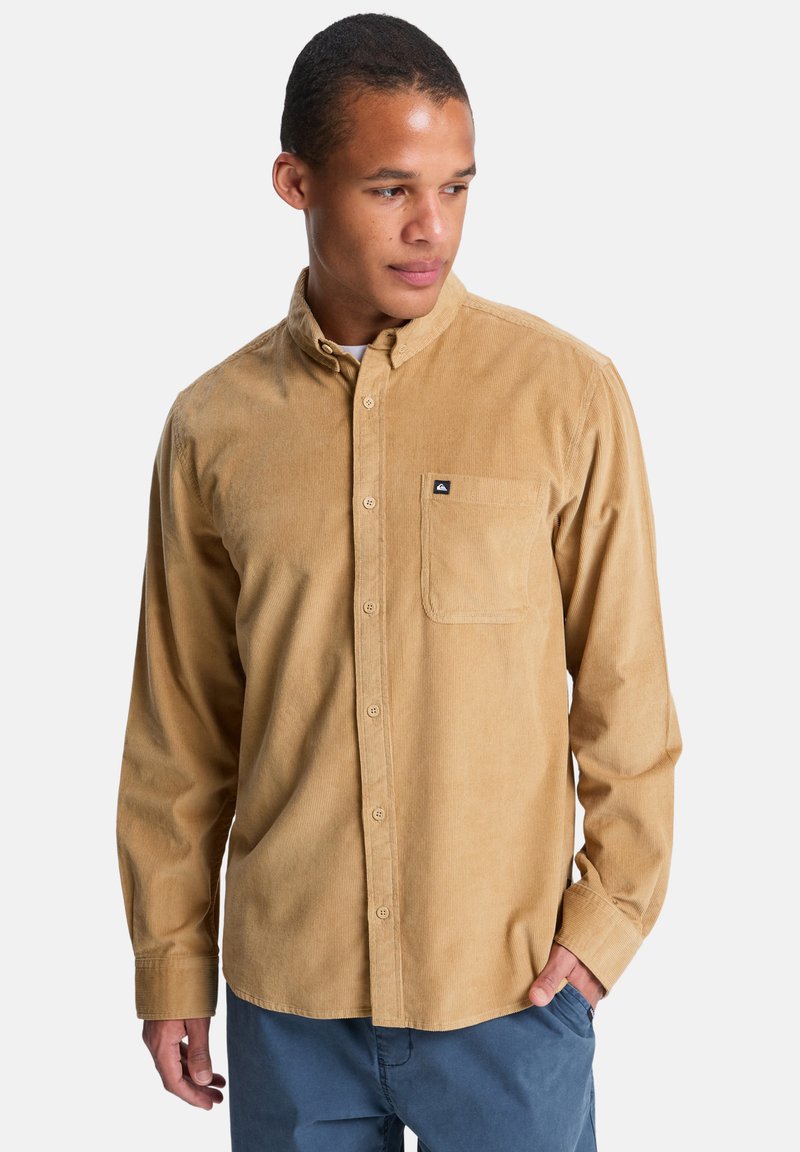 Καφέ χακί καρό πουκάμισο με κουμπιά, γιακά, μονό τσέπη στο στήθος και διακριτικό υφασμάτινο σχέδιο· φωτογραφημένο μπροστά σε λευκό φόντο.