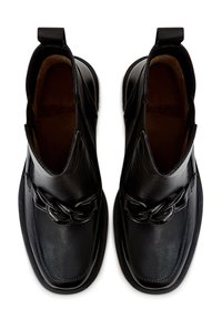 Botas de cuero negras hasta el tobillo con textura suave, que cuentan con un acento decorativo de cadena, punta redonda y una lengüeta en el talón para facilitar el uso.