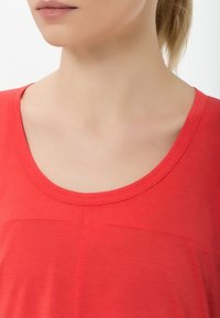 Top corto de manga corta rojo con cuello redondeado, textura suave y un sutil detalle de costura horizontal en la parte frontal.