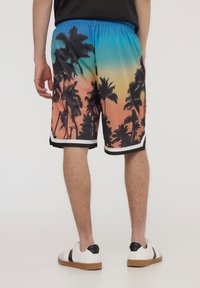 I pantaloni corti da uomo presentano un vivace gradiente che va dal blu all'arancione, realizzati in un tessuto a rete testurizzato, con una stampa di silhouette di palme e un bordo nero a contrasto.