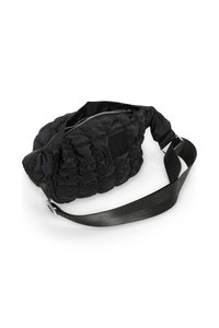 Sac en nylon noir matelassé avec une texture capitonnée, doté d'une fermeture zippée, d'une sangle réglable et d'un corps rectangulaire avec un patch de marque.