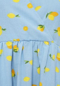 Μπλε ύφασμα με μοτίβο από κίτρινα λεμόνια και φέτες πορτοκαλιού. Το υλικό έχει απαλή υφή και περιλαμβάνει ρίγα στη μέση.