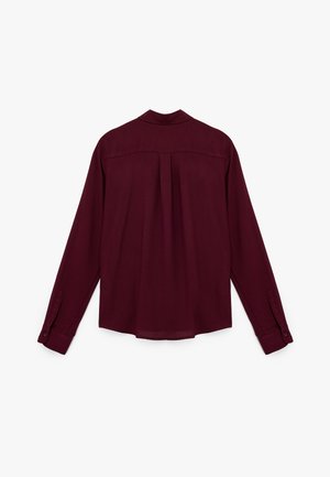 Burgundy long-sleeve shirt with a back pleat, button cuffs, and a classic collar. Smooth fabric with a flowing design.