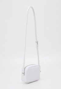 Borsa a tracolla bianca di forma rettangolare, realizzata in materiale sintetico liscio, con chiusura a zip; presenta una tracolla regolabile.