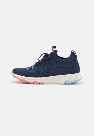 Granatowy dzianinowy sneaker z sznurowadłami, nakrapiana biała podeszwa, różowo-niebieski gumowy bieżnik, pętelki do ściągania na języku i pięcie.