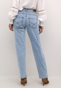Jeans azzurri chiari a gamba dritta realizzati in denim, caratterizzati da due tasche posteriori con dettagli cuciti e una finitura leggermente consumata.