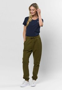 Marineblauwe katoenen t-shirt met korte mouwen en een klein logo, gecombineerd met olijfgroene, taps toelopende joggers met een verstelbare tailleband en enkelboordjes.