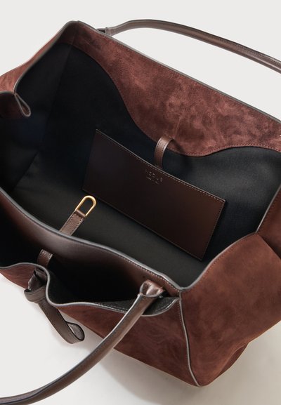 Sac cabas en daim et cuir marron avec intérieur noir, longues poignées, poche intérieure et détail anneau de clé doré à l'intérieur.