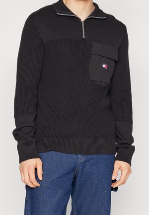 Pullover nero in maglia con colletto a mezza zip, tessuto testurizzato, taschino applicato sul lato sinistro del petto e polsini e orlo a coste.